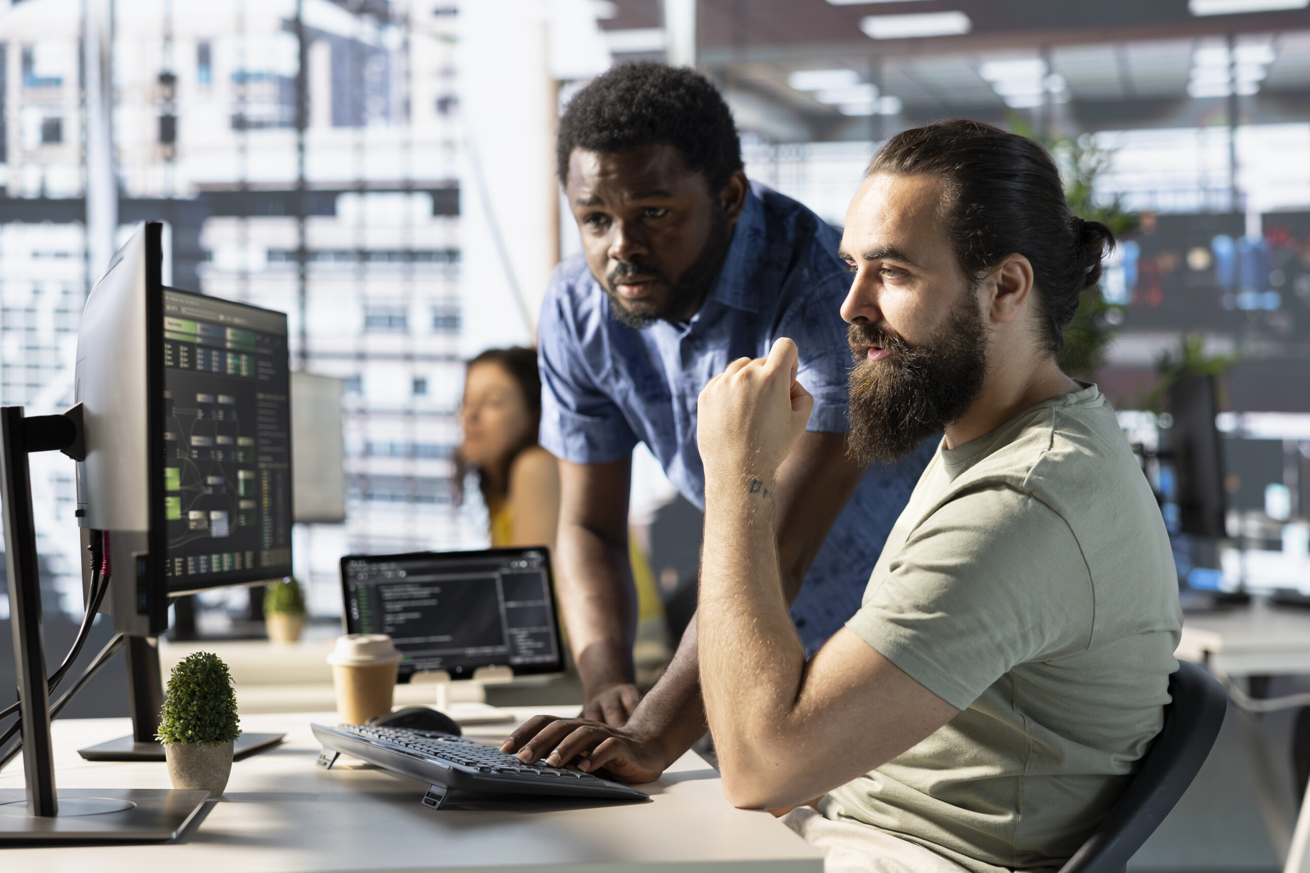 Two cloud engineers collaborating at a workstation with system architecture dashboards and code on screen in a modern office, representing legacy system modernization and digital transformation services by Sherdil Cloud. Two cloud engineers collaborating at a workstation with system architecture dashboards and code on screen in a modern office, representing legacy system modernization and digital transformation services by Sherdil Cloud.