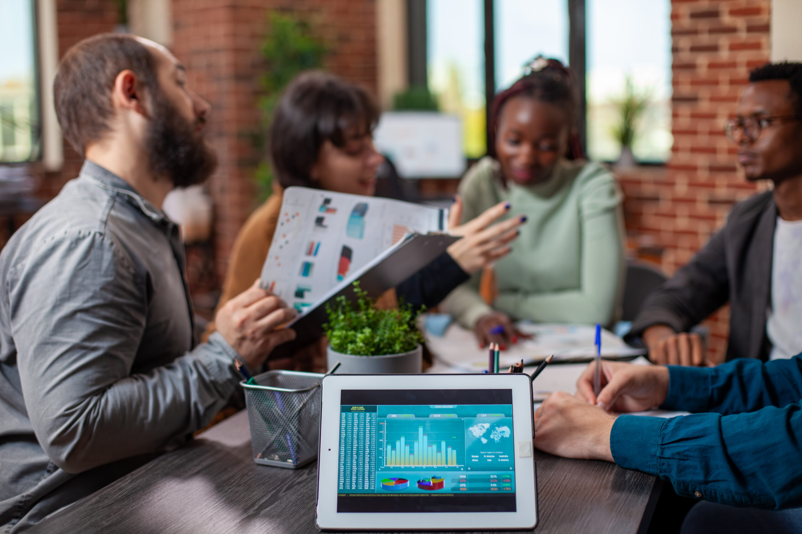 A tablet displaying a colorful business analytics dashboard sits on a meeting table in the foreground, while a diverse team of professionals collaborates in the background, symbolizing data-driven decisions to maximize ROI through smarter cloud infrastructure. A tablet displaying a colorful business analytics dashboard sits on a meeting table in the foreground, while a diverse team of professionals collaborates in the background, symbolizing data-driven decisions to maximize ROI through smarter cloud infrastructure.