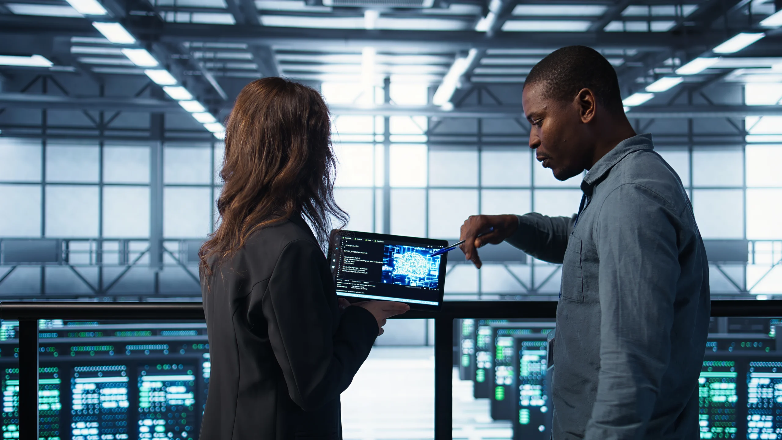 Two cloud engineers reviewing architecture diagrams on a tablet inside a data center, representing a hands-on comparison of AWS, Azure, and GCP cloud platforms in 2026.