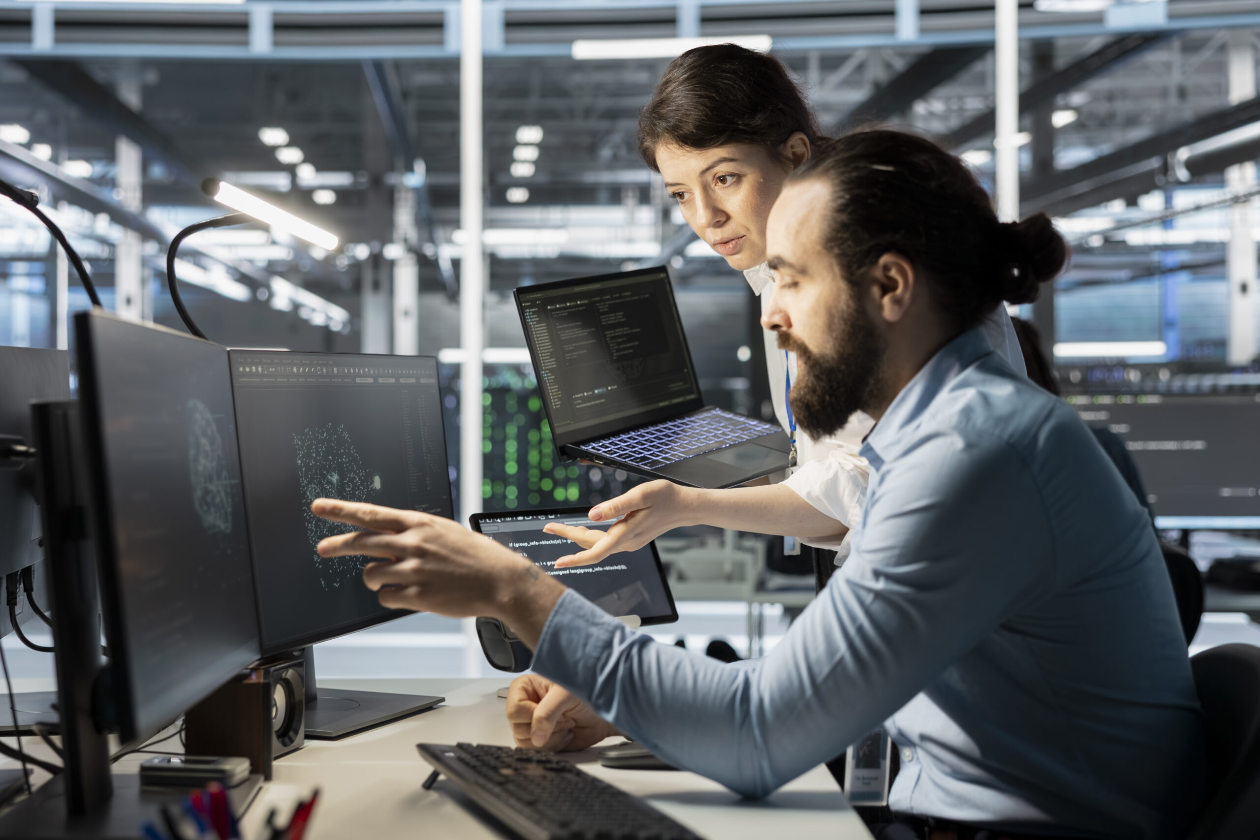Two DevOps engineers collaborating at a workstation with multiple monitors displaying system architecture and code, representing DevOps best practices for startups in 2026.